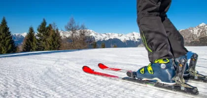 Skis et chaussures de ski sur une piste enneigée devant les montagnes.